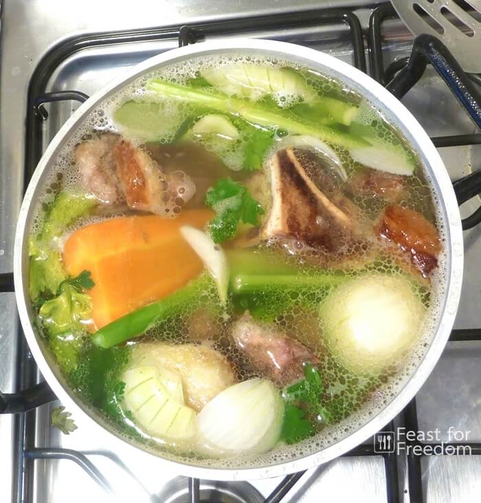 Beef stock cooking in a pot on a stove