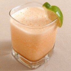 Cantaloupe smoothie in a glass with a lime garnish