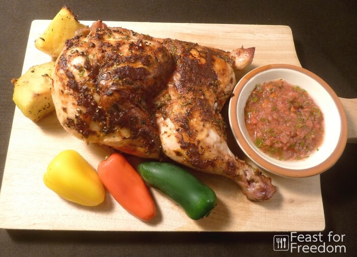 Baked chicken basted with fresh salsa on a wooden cutting board