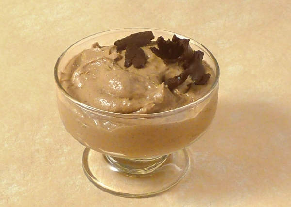 Nut butter and banana pudding in a simple bowl, topped with large grated chocolate chunks
