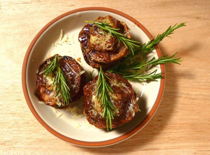 Purple sweet potato stackers on a plate sprinkled with Parmesan cheese and a sprig of fresh rosemary