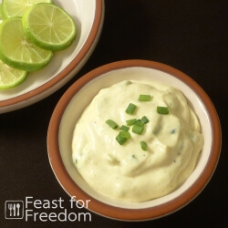 Tartar sauce in a bowl with sliced limes